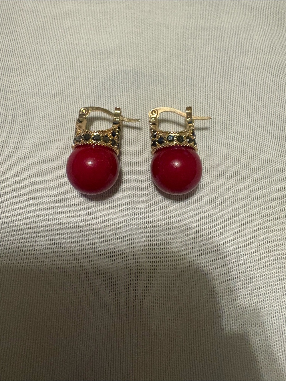 Gold-tone crown-style huggie earrings with red bead drops and rhinestone details